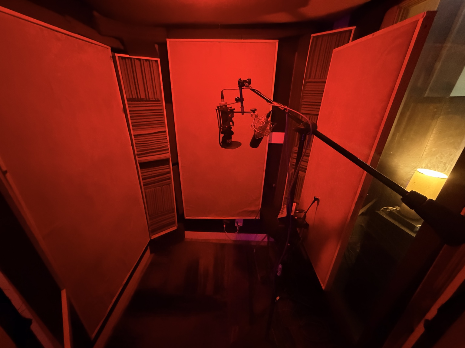 Red-lit vocal booth with acoustic panels and a recording microphone at Chokobeats